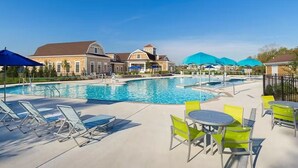 A swimming pool with lounge chairs and tables, surrounded by buildings with a classic architectural style. - New 2025 Beach Home! Ocean View Beach Club! 5 Minutes to Bethany Beach (Ocean View)