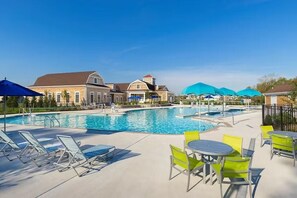 A swimming pool with lounge chairs and tables, surrounded by buildings with a classic architectural style. - New 2025 Beach Home! Ocean View Beach Club! 5 Minutes to Bethany Beach (Ocean View)