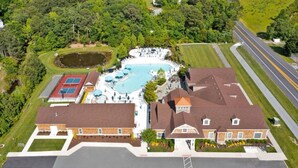 An aerial view of a residential property with a swimming pool, tennis courts, and a large house with a red roof. - New 2025 Beach Home! Ocean View Beach Club! 5 Minutes to Bethany Beach (Ocean View)