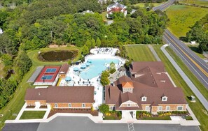 An aerial view of a residential property with a swimming pool, tennis courts, and a large house with a red roof. - New 2025 Beach Home! Ocean View Beach Club! 5 Minutes to Bethany Beach (Ocean View)