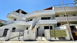 Ein mehrgeschossiges Wohngebäude mit modernem Design, das eine zentrale Treppe und mehrere Balkone zeigt.