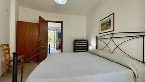 Ein Schlafzimmer mit einem Bett, einer Holztür, einem Sessel und einer Heizung.
