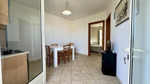Eine kompakte Küche mit Essbereich, einem kleinen Fernseher und einer Tür zum Schlafzimmer.
