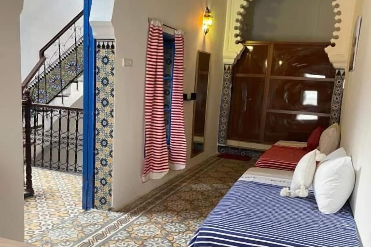 Una habitació amb un llit, una escala i vista a un pati.