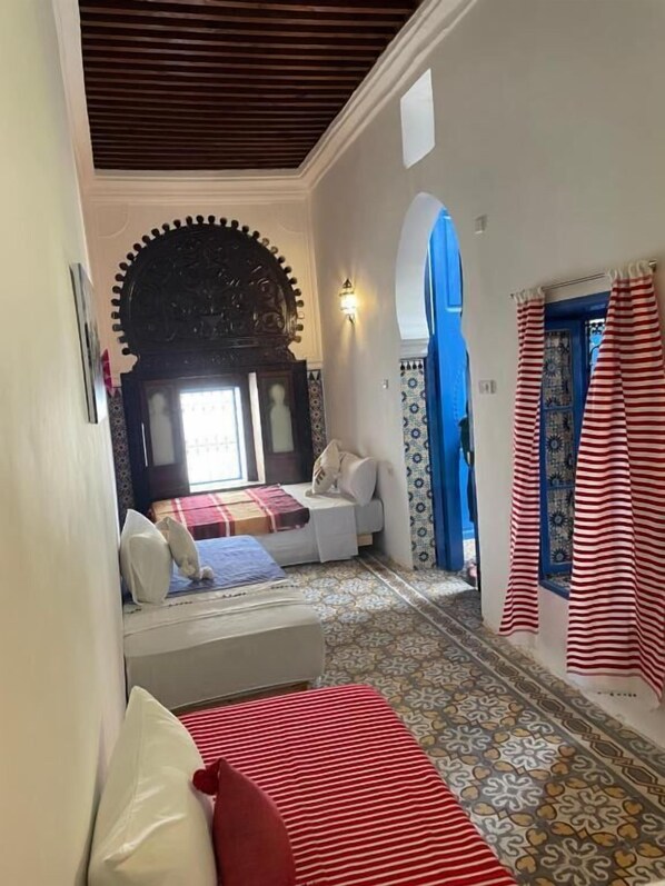 A bedroom with a bed, a sofa, and a patterned floor.