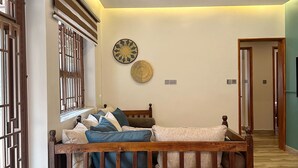 Ein modernes Wohnzimmer mit einem Holzsofa, zwei Sesseln, einem Deckenventilator und dekorativen Wandplatten.