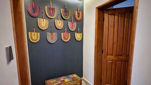Ein Flur mit einer Holzbank, einer Holztür und einer Wand, die mit bunten gewebten Körben verziert ist.