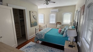 A bedroom with a bed, bedside table, lamp, and a window with blinds.