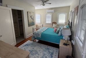 Un dormitorio con cama, mesita de noche, lámpara y ventana con persianas.