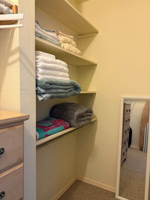 A closet with shelves holding folded towels and blankets.