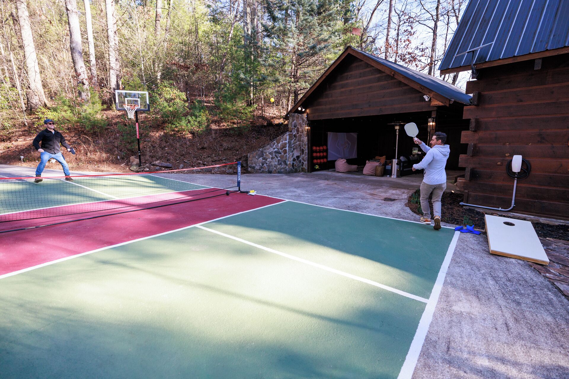 An outdoor tennis court with a wooden cabin in the background.