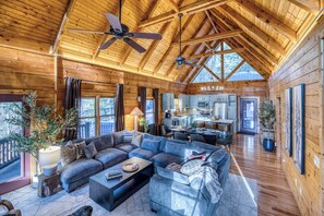 Un intérieur spacieux de chalet en bois, comprenant un grand salon, une cuisine et un coin repas.