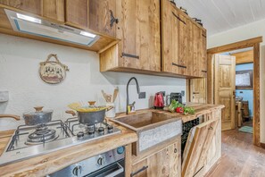 A kitchen with wooden cabinets, a gas stove, a sink, and a window. - Luna Apartment Baita Ayana with Balcony Views, Oulx, Italy (Oulx)