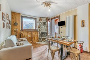Ein gemütlicher Wohnraum mit Kamin, Holzmöbeln und einem Essbereich mit Tisch und Stühlen.