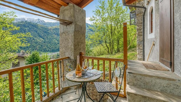A balcony with a table set for two, a bottle, and glasses, overlooking a mountainous landscape. - Luna Apartment Baita Ayana with Balcony Views, Oulx, Italy (Oulx)