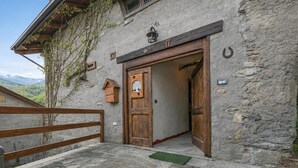 A rustic stone building with a wooden door, a small bell, and a number '11' sign. - Luna Apartment Baita Ayana with Balcony Views, Oulx, Italy (Oulx)