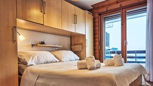 Un letto rifatto con un piumone bianco strutturato, una testiera in legno e un piccolo ripiano sopra.