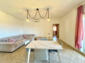 Ein modernes Wohnzimmer mit einem beigen Ecksofa, einem weißen Marmorestisch und einer Deckenleuchte.
