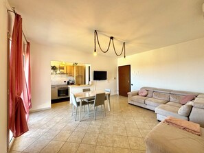 Ein modernes Wohnzimmer mit einem beigefarbenen Sofa und einem Essbereich mit Tisch und Stühlen.
