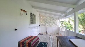 Uma área de estar ao ar livre coberta, com um banco, uma mesa e uma cadeira.