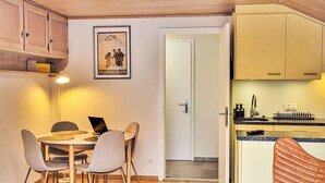 Eine kleine Küche mit Holzausstattung, eine Essecke mit Tisch und Stühlen sowie ein Poster an der Wand.