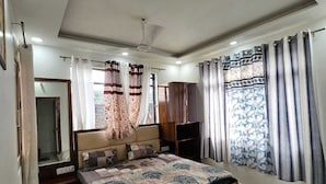 Un dormitorio con cama, ventilador de techo, armario y ventana con cortinas.