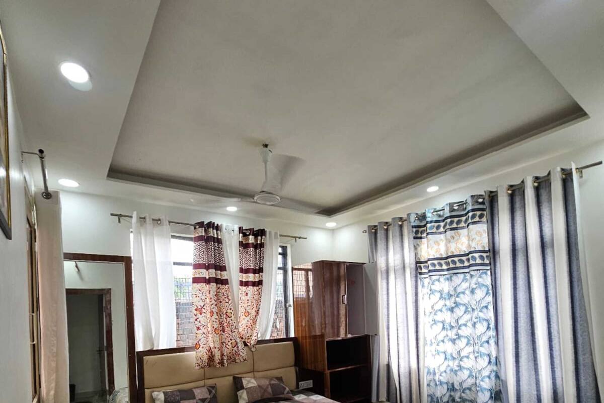 A bedroom with a bed, a ceiling fan, a wardrobe, and a window with curtains.