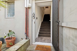 Entrada de un edificio residencial con una escalera de madera que sube a un segundo piso.