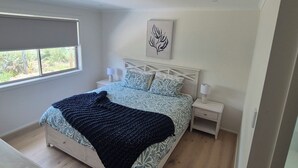 A bedroom with a bed, bedside tables, a window, and a wall-mounted artwork. - Golden Beach Holiday Home (Golden Beach)
