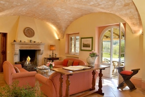 A cozy living room with a fireplace, a dining table, and comfortable seating. - Beautiful detached farmhouse 10 km from the sea. Heated infinity pool and breathtaking views! (Guardistallo)
