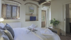 Un dormitorio con cama, una ventana, estante con un certificado enmarcado y planta en maceta.