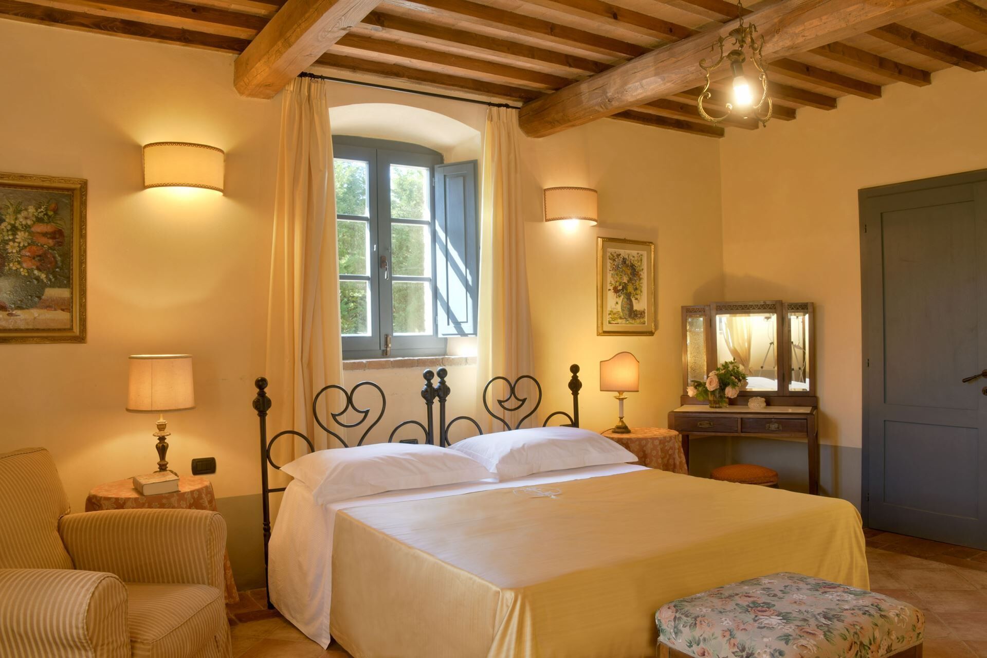 Un dormitorio con una cama, dos lámparas de noche, un aparador, un espejo y una ventana con cortinas.