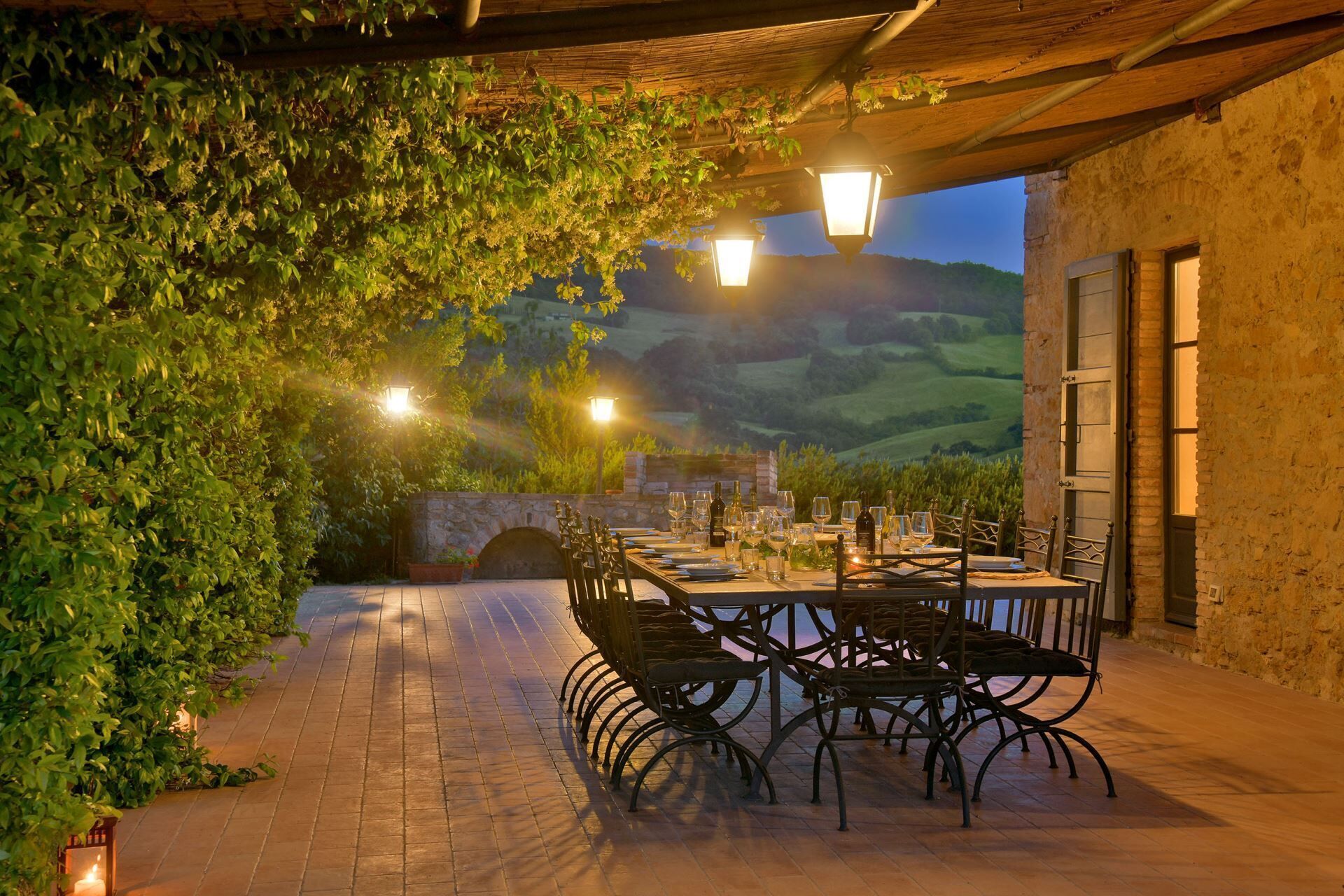 An outdoor dining area with a stone wall, metal chairs, and tables set for a meal.