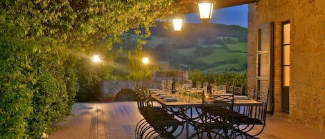 An outdoor dining area with a stone wall, metal chairs, and tables set for a meal.