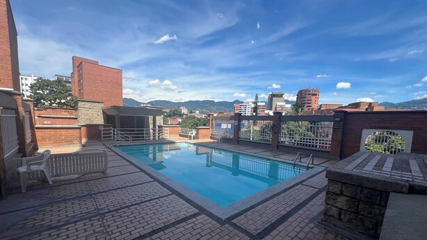 Una piscina sul tetto con vista panoramica sulla città e montagne sullo sfondo.