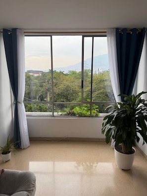 A room with a large window, a potted plant, and a sofa. - Private 2BR Apartment · Quiet · Prime Location (Medellín)