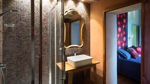 Un baño con cabina de ducha de vidrio, lavamanos blanco y un espejo grande.
