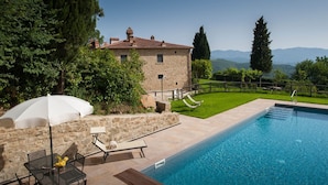 A stone villa with a swimming pool, outdoor seating, and a view of mountains. - Podere della Rosa: elegance and comfort in the Tuscan hills (Arezzo)