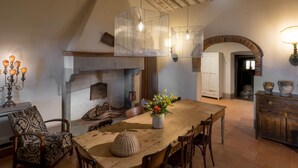 A rustic dining area with a wooden table, chairs, and a hanging light fixture. - Podere della Rosa: elegance and comfort in the Tuscan hills (Arezzo)