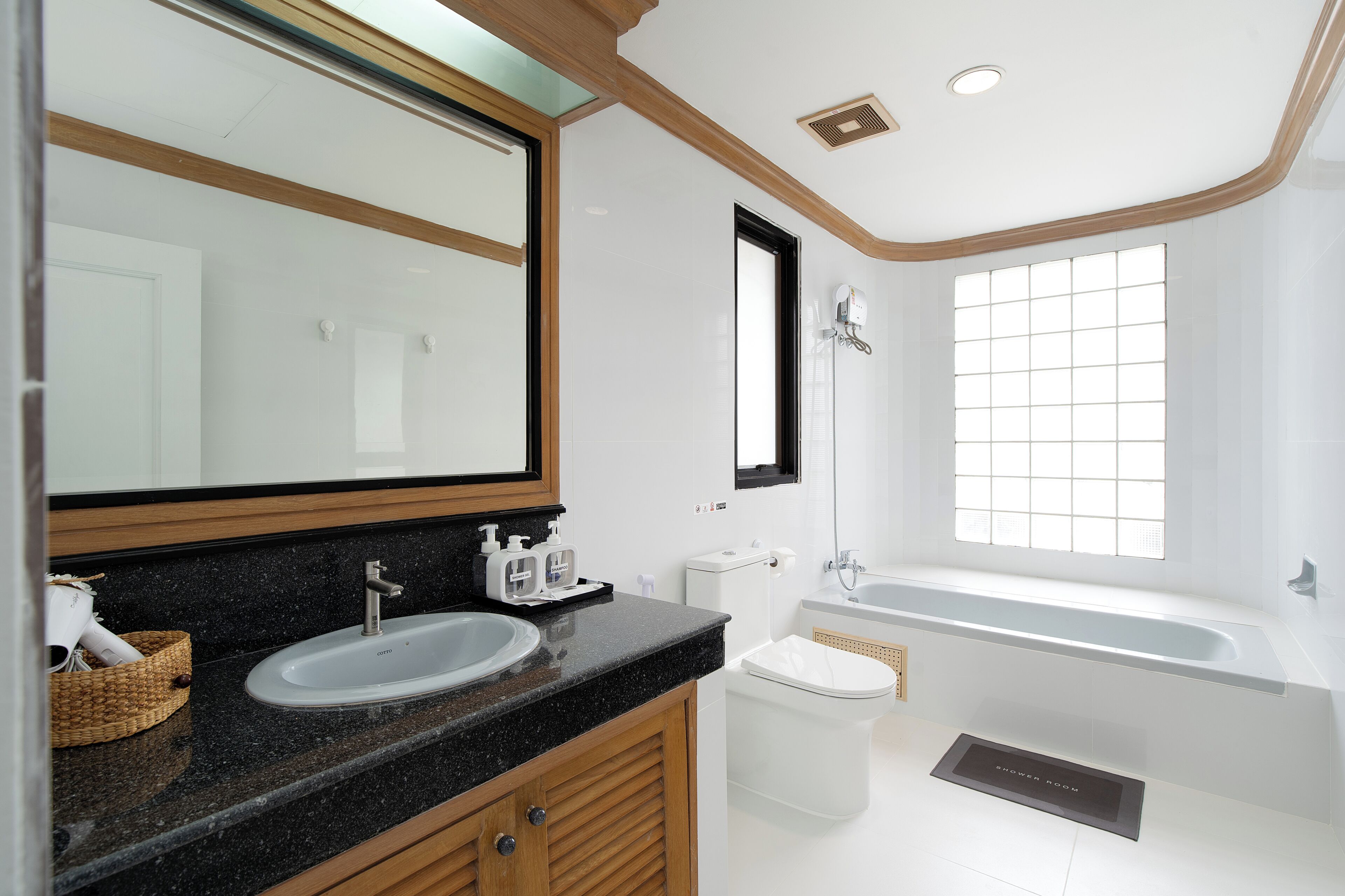 A modern bathroom with a large mirror, two sinks, a toilet, and a bathtub.