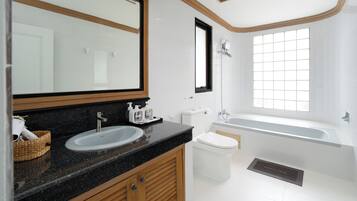 A modern bathroom with a large mirror, two sinks, a toilet, and a bathtub.