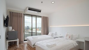 A modern hotel room with two beds, a TV, and a city view. - Bed to Bliss (Bangkok)