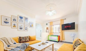 A living room with a sofa, a coffee table, and a TV displaying 'NETFLIX'. - Studio  Élégant, Vue Mer & Plage à 5 min (agadir)