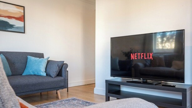 Una sala de estar moderna con un sofá gris, un televisor de pantalla plana y un diseño minimalista.