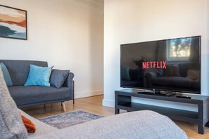 A modern living room with a grey sofa, a flat-screen TV, and a minimalist design. - Atlanta's Residence by Tŷ SA (Newport)