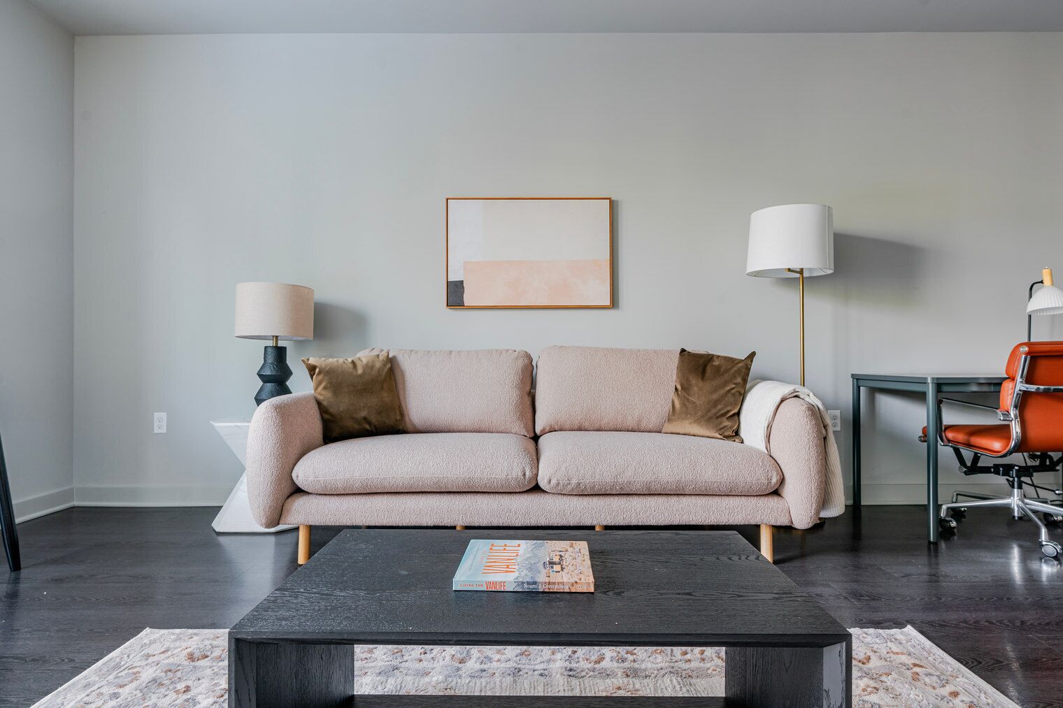 Una sala de estar moderna con sofá, mesa de centro y lámparas.