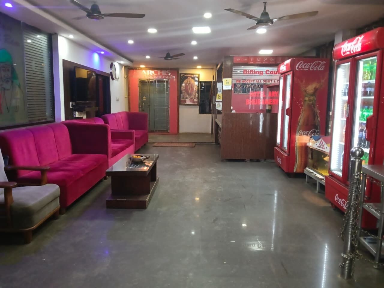 A lobby with a red sofa, a small table, and a Coca-Cola vending machine.