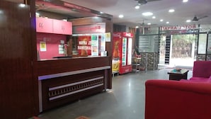 A hotel lobby with a reception desk, a Coca-Cola refrigerator, and a red sofa. - Aryan (Bhubaneshwar)