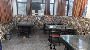 A restaurant with stone walls, multiple tables and chairs, and large windows with curtains. - Aryan (Bhubaneshwar)