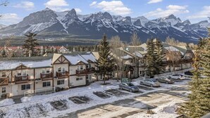 Un hotel con vistas a la montaña, varios balcones y un estacionamiento.